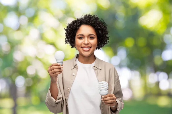 Feliz mulher segurando lâmpadas de iluminação sobre verde — Fotografia de Stock