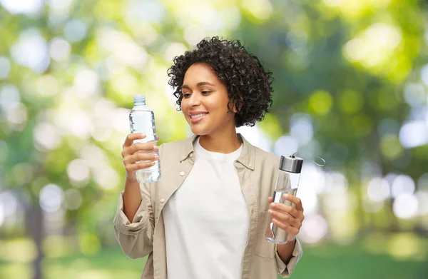 Femme heureuse avec de l'eau en verre et bouteille en plastique — Photo