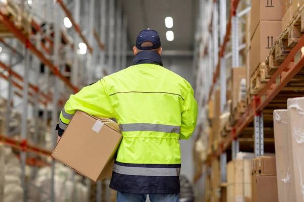 Hombre en uniforme con caja en el almacén — Foto de Stock