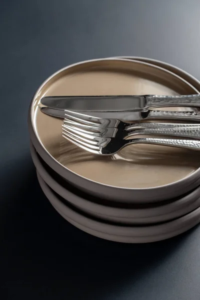 Płyty ceramiczne, widelce i noże na czarnym stole — Zdjęcie stockowe