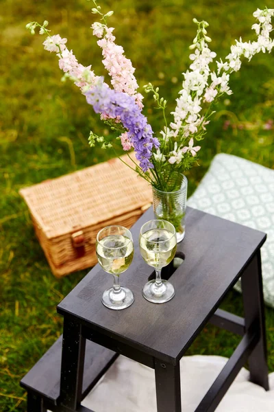 Cestino da picnic, fiori e bicchieri di vino al parco — Foto Stock