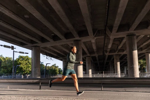 Young man running outdoors under bridge — Stock Photo, Image