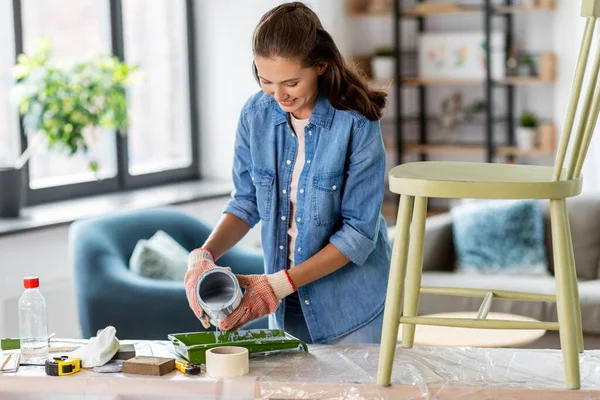 Mujer feliz verter pintura gris para bandeja en casa —  Fotos de Stock