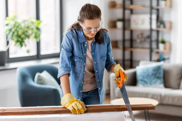 Woman with saw sawing wooden board at home — Stock Photo, Image