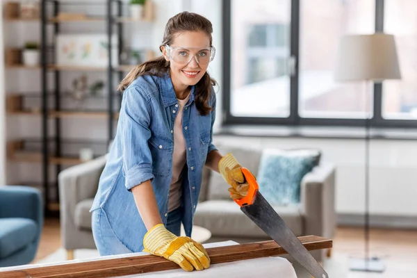 Kvinna med såg sågning träskiva hemma — Stockfoto