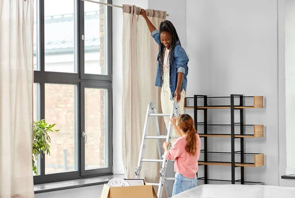 Vrouw op ladder gordijnen opknoping thuis — Stockfoto