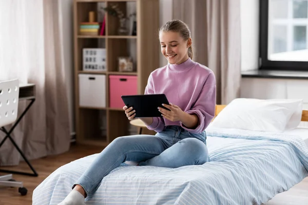 Mosolygós lány tabletta pc ül az ágyon otthon — Stock Fotó