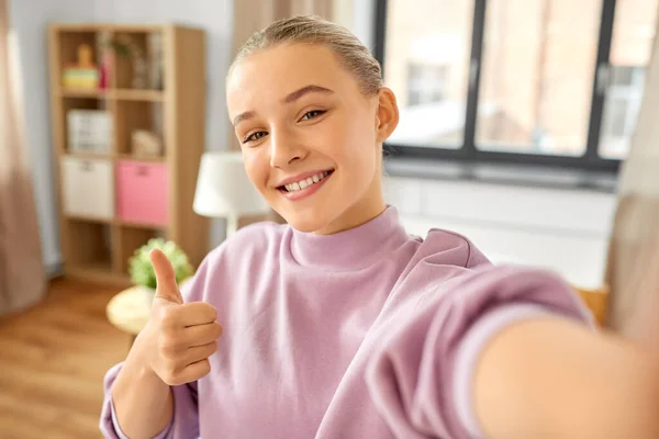 Meisje nemen selfie en tonen duimen tot in huis — Stockfoto