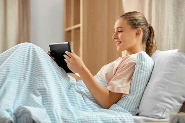 Chica feliz con la computadora PC tableta en la cama en casa —  Fotos de Stock