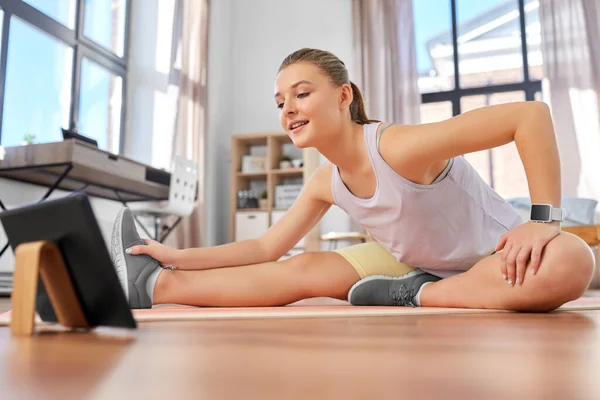 Teenage girl with tablet pc exercising at home — Stock Photo, Image