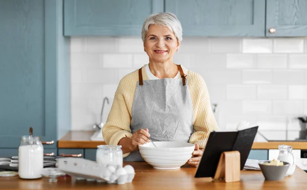 Счастливая женщина с кулинарной книгой для приготовления пищи на кухне — стоковое фото