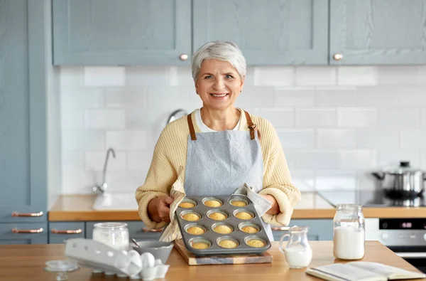 Женщина с кексами в выпечке плесени на кухне — стоковое фото