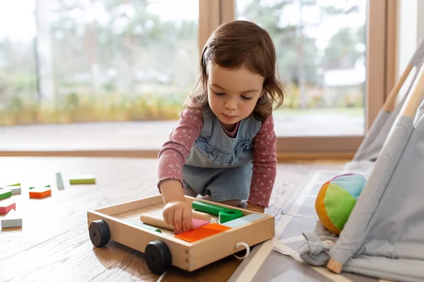 Щаслива дівчинка грає з іграшковими блоками вдома — стокове фото