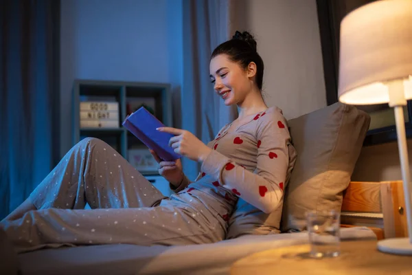 Feliz adolescente leyendo libro en la cama en casa —  Fotos de Stock