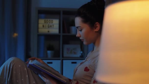 Adolescente menina ler livro na cama à noite — Vídeo de Stock