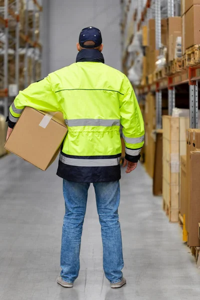 Man in uniform with box at warehouse — Stock Photo, Image
