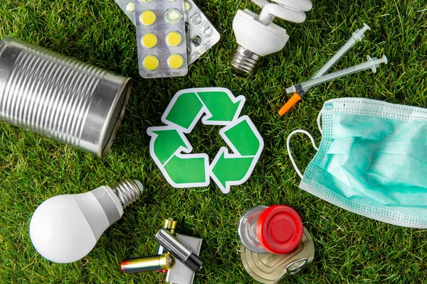 Letrero de reciclaje verde con residuos domésticos en hierba — Foto de Stock