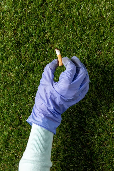 Close up of hand in glove picking cigarette butt — Stock Fotó