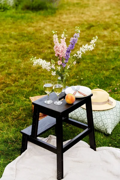 Piknikový koš, květiny a sklenice na víno v parku — Stock fotografie
