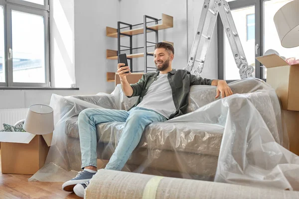 Lächelnder Mann mit Smartphone bezieht neues Zuhause — Stockfoto