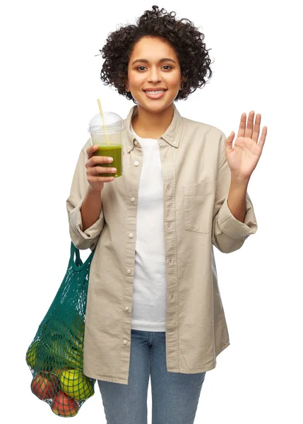 Женщина с многоразовым пакетом для покупок пьет смузи — стоковое фото
