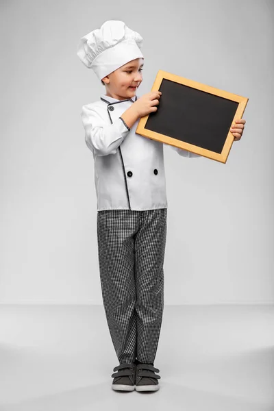 Niño feliz en chefs toque con pizarra —  Fotos de Stock