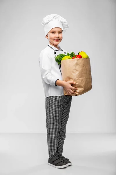 Menino feliz em chefs toque com comida no saco — Fotografia de Stock