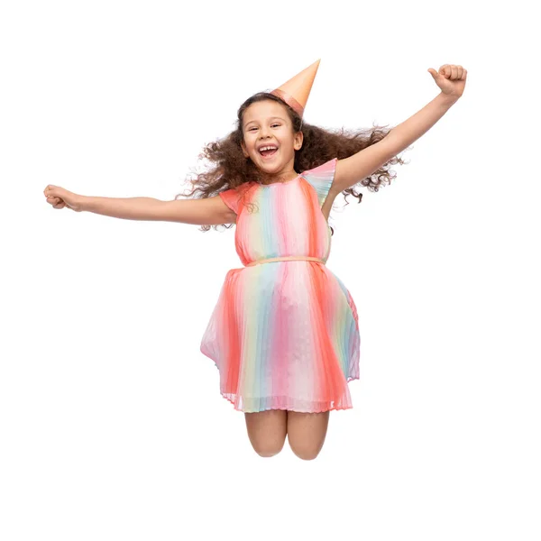 Smiling little girl in birthday party hat jumping — Stock Photo, Image