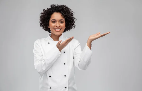Leende kvinnlig kock håller något på handen — Stockfoto