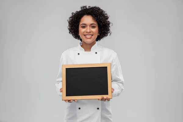 Sorridente chef donna con lavagna nera in mano — Foto Stock