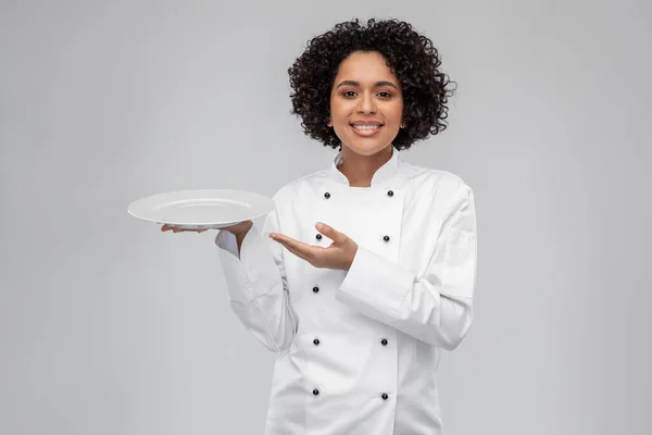 Счастливая улыбающаяся женщина-повар держит пустую тарелку Лицензионные Стоковые Изображения