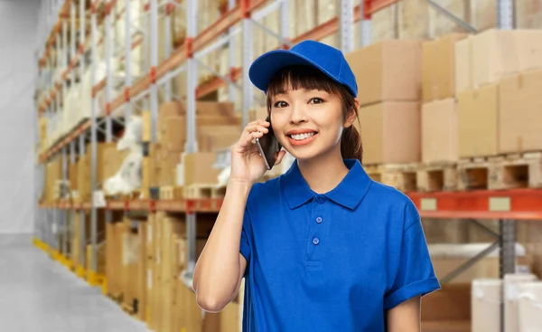 Mulher de entrega feliz chamando no telefone no armazém — Fotografia de Stock
