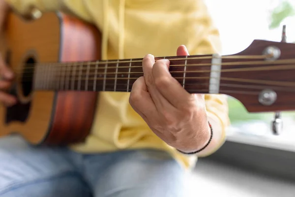 Zbliżenie człowiek gra na gitarze siedzi na parapecie — Zdjęcie stockowe