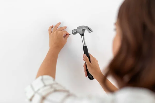 Primer plano de la mujer clavando clavos a la pared en casa —  Fotos de Stock