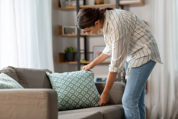 Счастливая женщина устраивает подушки дома — стоковое фото