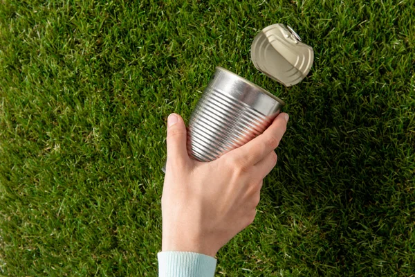 Close up of hand removing used tin can from grass — Stock Photo, Image