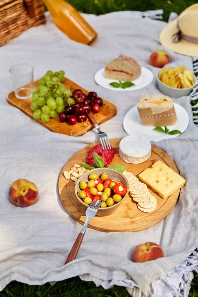 Їжа, напої та кошик для пікніка на ковдрі на траві — стокове фото