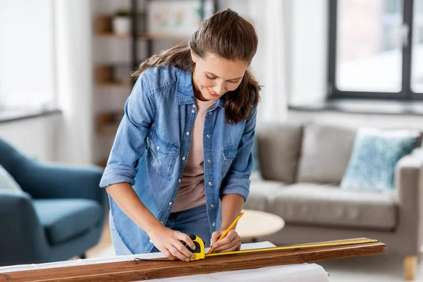 Woman with ruler measuring wooden board at home — Stock Photo, Image