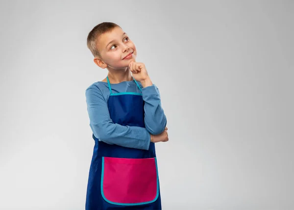Smiling little boy in apron thinking — Stock Photo, Image