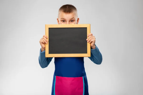 Little boy in apron holding chalkboard — Stock Photo, Image