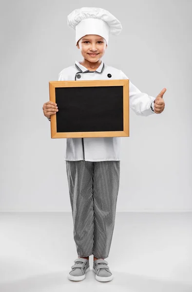 Happy little girl in chefs toque with chalkboard — Stock Photo, Image