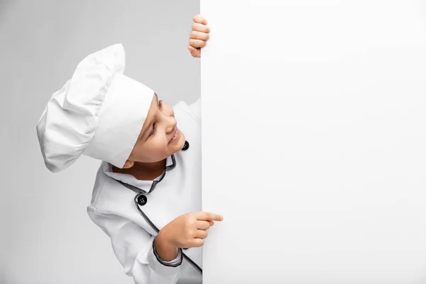 Menina feliz em chefs toque com placa branca — Fotografia de Stock