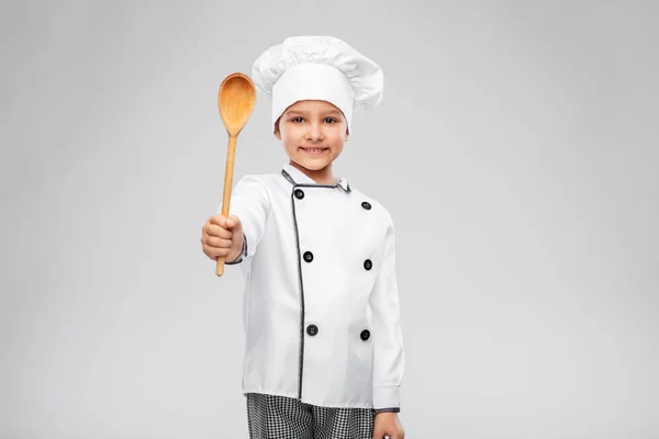 Niña sonriente en chefs toque con cuchara — Foto de Stock