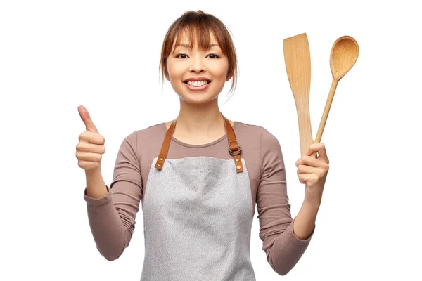 Mujer feliz en delantal con cuchara de madera y espátula —  Fotos de Stock