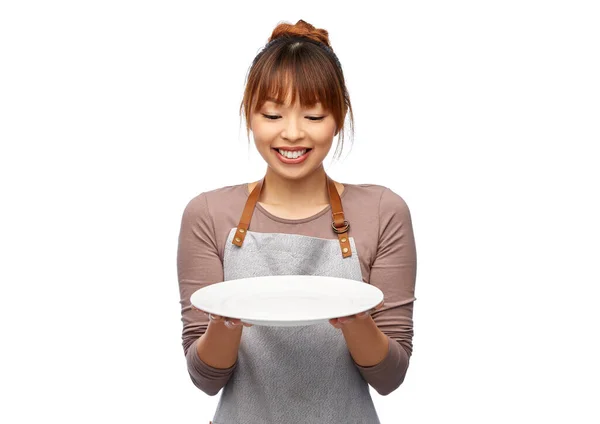 Mujer feliz en delantal con plato vacío —  Fotos de Stock