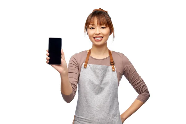 Lycklig kvinna i förkläde visar smartphone — Stockfoto