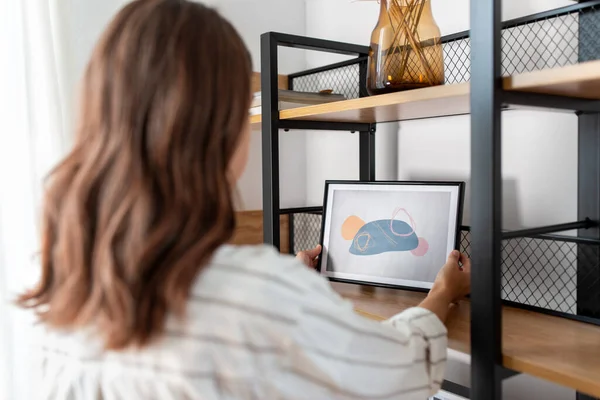 Vrouw versieren huis met foto in frame — Stockfoto