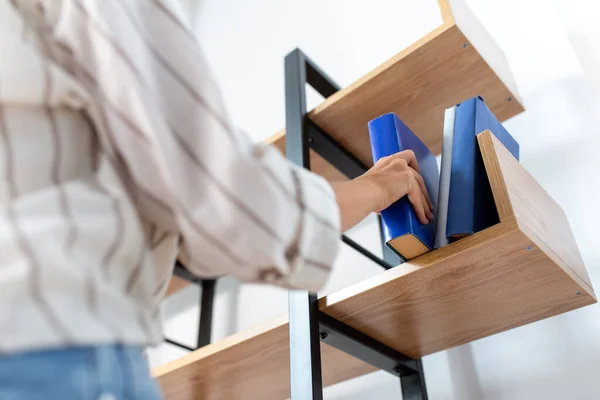 Frau arrangiert Bücher im Regal zu Hause — Stockfoto
