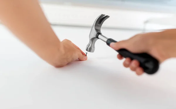 Крупним планом руки забивають цвях до стіни в домашніх умовах — стокове фото