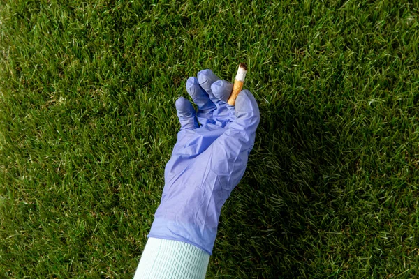 Close up of hand in glove picking cigarette butt — Stock Fotó
